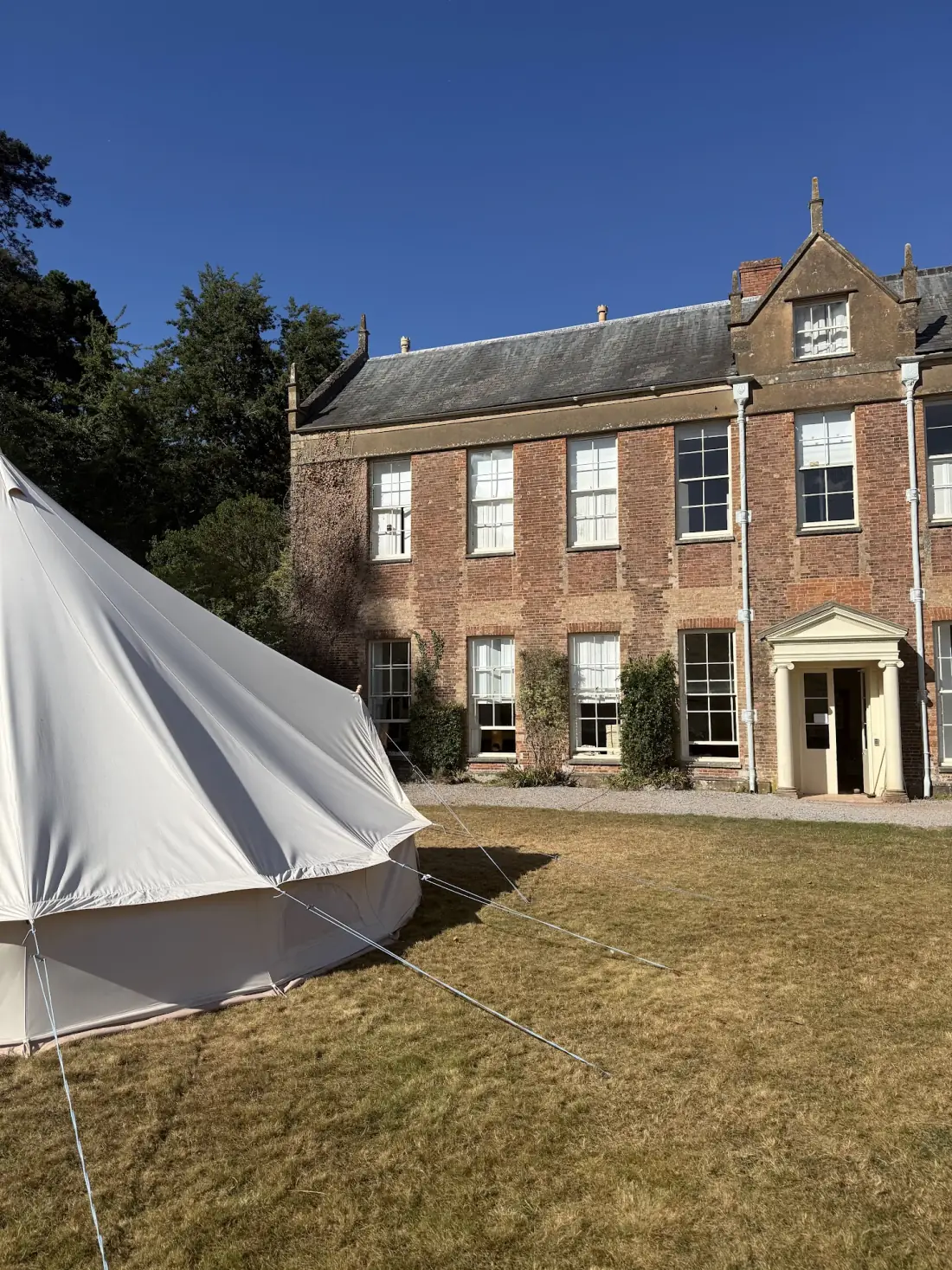 A bell tent pitched on the lawn in front of the manor